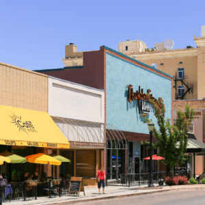 Grand Junction, USA - May 28, 2016: Cafe with outside dining and shops on the main street of the city. People are walking by.